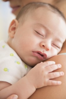 Baby boy (2-5 months) sleeping on mother's shoulder.