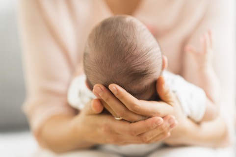Mother holding baby boy (2-5 months).
