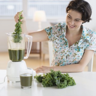 Woman preparing healthy drink with kale.
Photo : Jamie Grill
