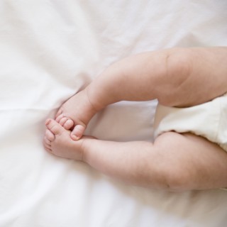 Feet of baby girl (2-5 months) lying on bed.
Photo : Jamie Grill