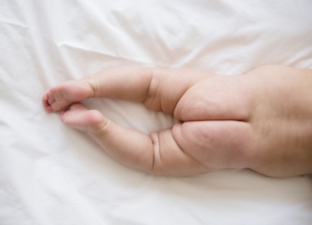 Legs and buttocks of baby girl (2-5 months) lying on bed.
Photo : Jamie Grill