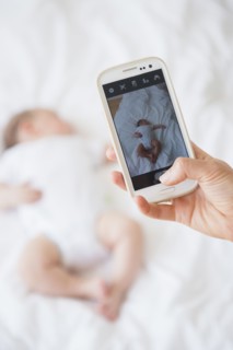 Mother photographing baby girl (2-5 months) sleeping in bed.
Photo : Jamie Grill