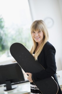 Businesswoman holding skateboard in office.
Photo : Jamie Grill