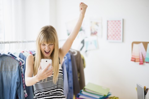 Woman looking at cell phone and cheering.
Photo : Jamie Grill