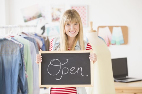 Portrait of female business owner holding open sign.
Photo : Jamie Grill