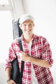 Portrait of man carrying guitar bag.
Photo : Daniel Grill
