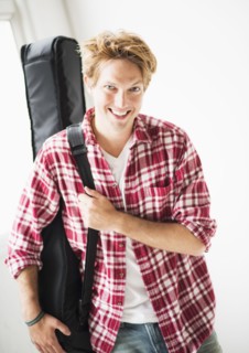 Portrait of man carrying guitar bag.
Photo : Daniel Grill