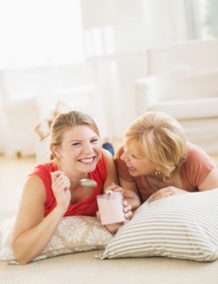 Mother and adult daughter relaxing at home, eating ice cream.
Photo : Daniel Grill