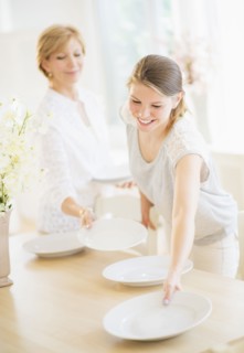 Mother and adult daughter setting table for dinner.
Photo : Daniel Grill