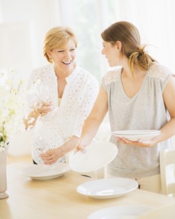Mother and adult daughter setting table for dinner.
Photo : Daniel Grill