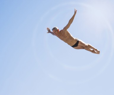 Athletic swimmer mid-air against blue sky.
Photo : Daniel Grill