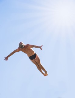 Athletic swimmer mid-air against blue sky.
Photo : Daniel Grill