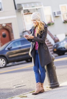 Portrait of woman standing by fire hydrant and text messaging. USA, New York City, Brooklyn,