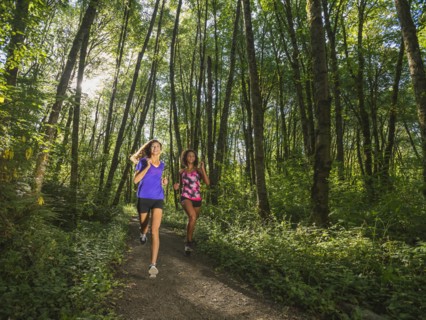 Two young women jogging in forest. USA, Oregon, Portland.