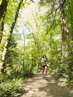Young woman jogging in forest. USA, Oregon, Portland.