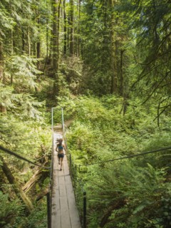 Rear view of young woman jogging in forest. USA, Oregon, Portland.