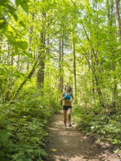 Young woman jogging in forest. USA, Oregon, Portland.