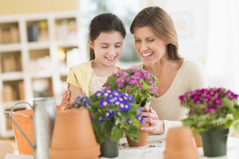 Girl (8-9) and mother potting flowers.