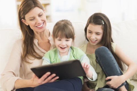 Mother and daughters (4-5, 8-9) using tablet pc.