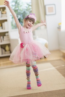 Girl (4-5) wearing tutu dancing in living room.