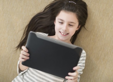 Girl (8-9) lying on floor using tablet pc.
