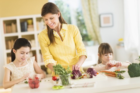 Mother and daughters (4-5, 8-9) cooking in kitchen.