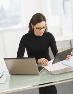 Businesswoman working on laptop and digital tablet.