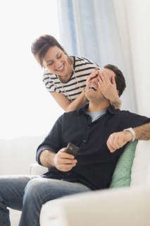 Woman covering man's eyes.