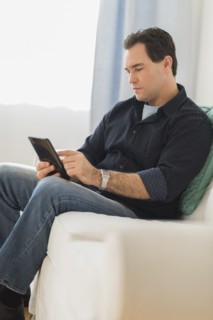 Man sitting on sofa looking at digital tablet.