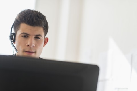 Young man sitting in front of desk and talking.