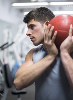Young man at gym holding medicine ball.