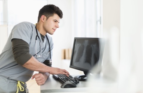 Young man with stethoscope working at computer.