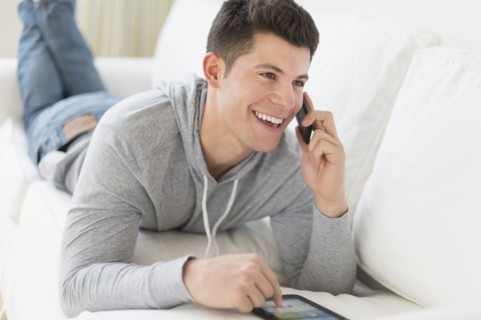 Young man using tablet and talking by phone.
