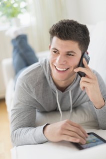 Young man using tablet and talking by phone.