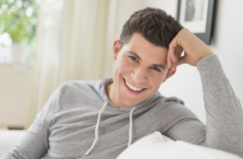 Young man sitting on sofa and smiling.