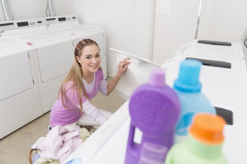 Woman loading laundry into washing machine.