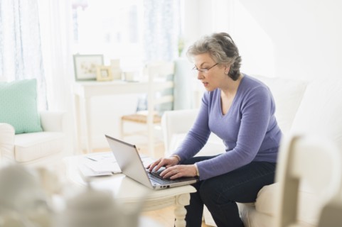 Mature woman paying bills via internet.