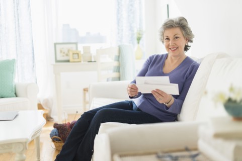 Woman sitting on coach reading letters.