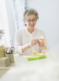 Mature woman reading labels on medicine bottle.