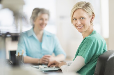 Portrait of female doctor, patient in background.