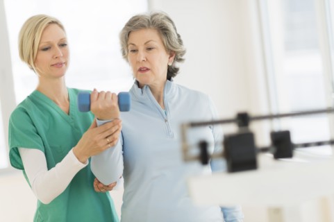 Mature woman exercising with personal trainer.