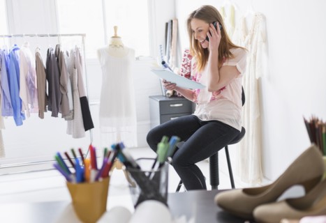 Portrait of female costume designer using mobile phone in studio.
