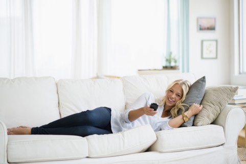 Young woman watching tv on sofa.
Photo : Jamie Grill
