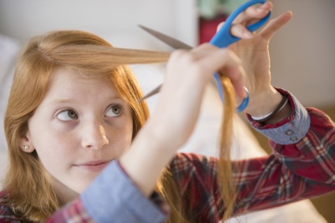 Portrait of girl (12-13) cutting her hair.
Photo : Jamie Grill