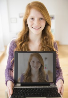 Portrait of girl (12-13) holding laptop.
Photo : Jamie Grill