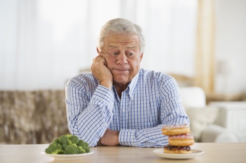 Portrait of senior man looking at doughnut.
Photo : Jamie Grill