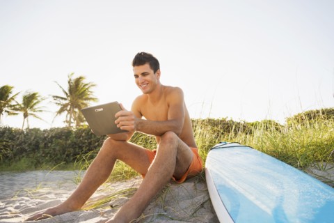 Young man sitting on beach with surfboard and digital tablet. Jupiter, Florida, USA.
Photo :