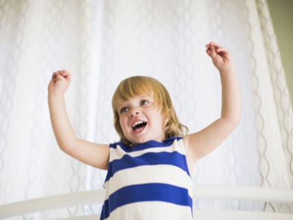 Portrait of girl (4-5) with arms raised.
Photo : Jessica Peterson