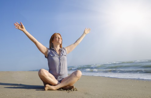Woman practicing yoga on beach.