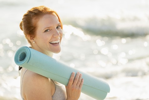 Portrait of woman holding yoga mat.